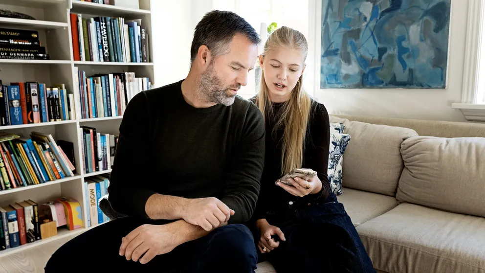 En voksen og et barn kigger på en telefon.