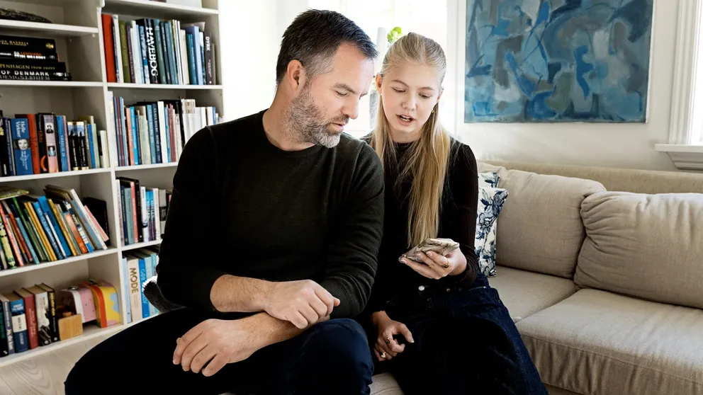 En voksen og et barn kigger på en mobiltelefon.