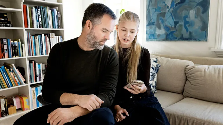 En voksen og et barn kigger på en mobiltelefon.