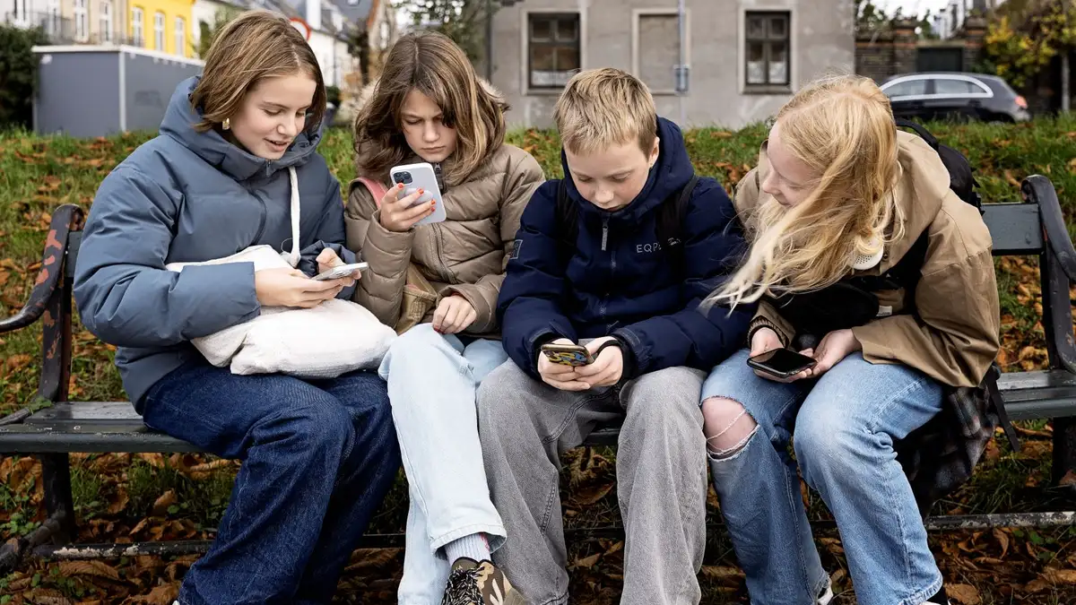 Fire børn kigger på deres telefoner.